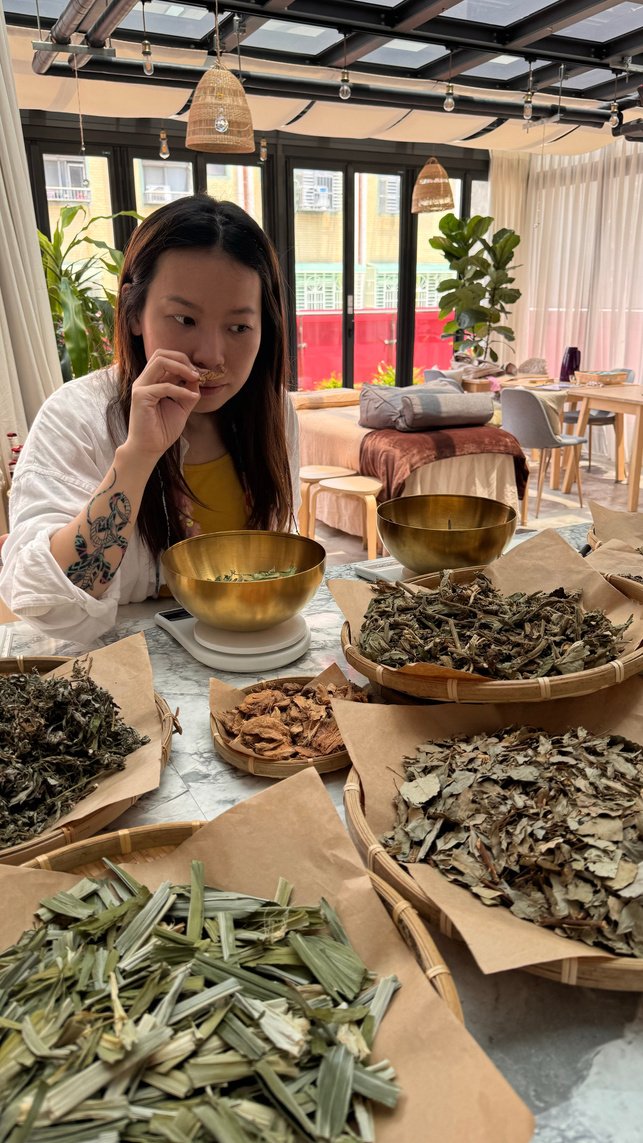 Una selecting and smelling herbs for a compress ball