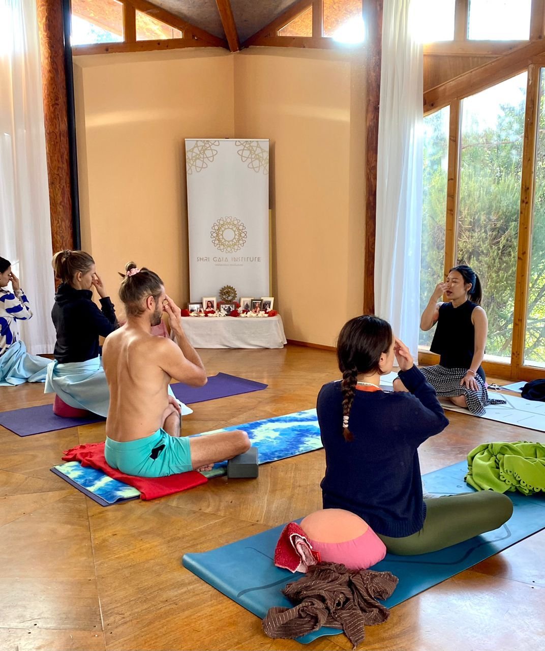 A group seated in pranayama practice in a residential training room